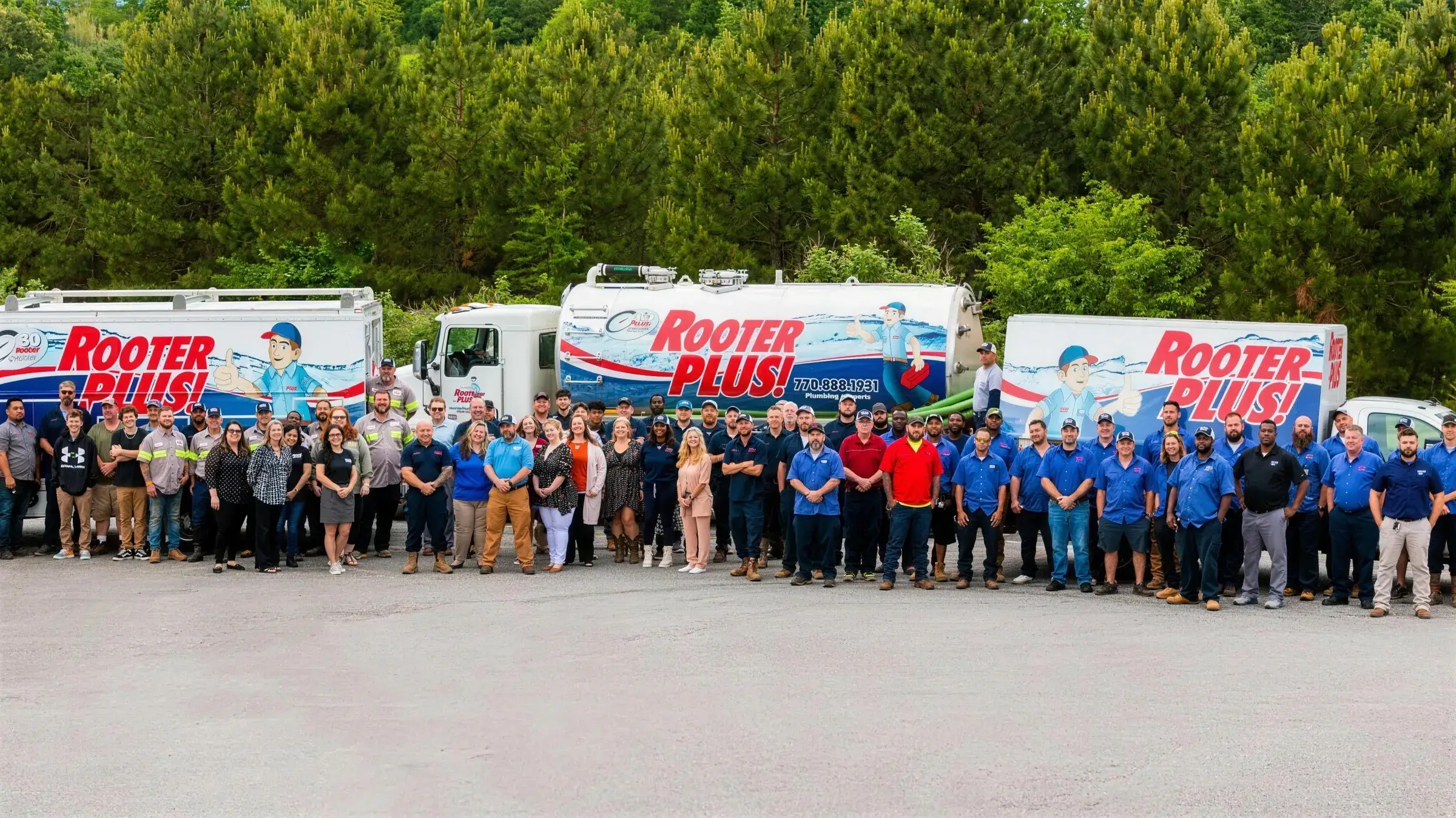 The RooterPLUS team standing in front of the company's service trucks