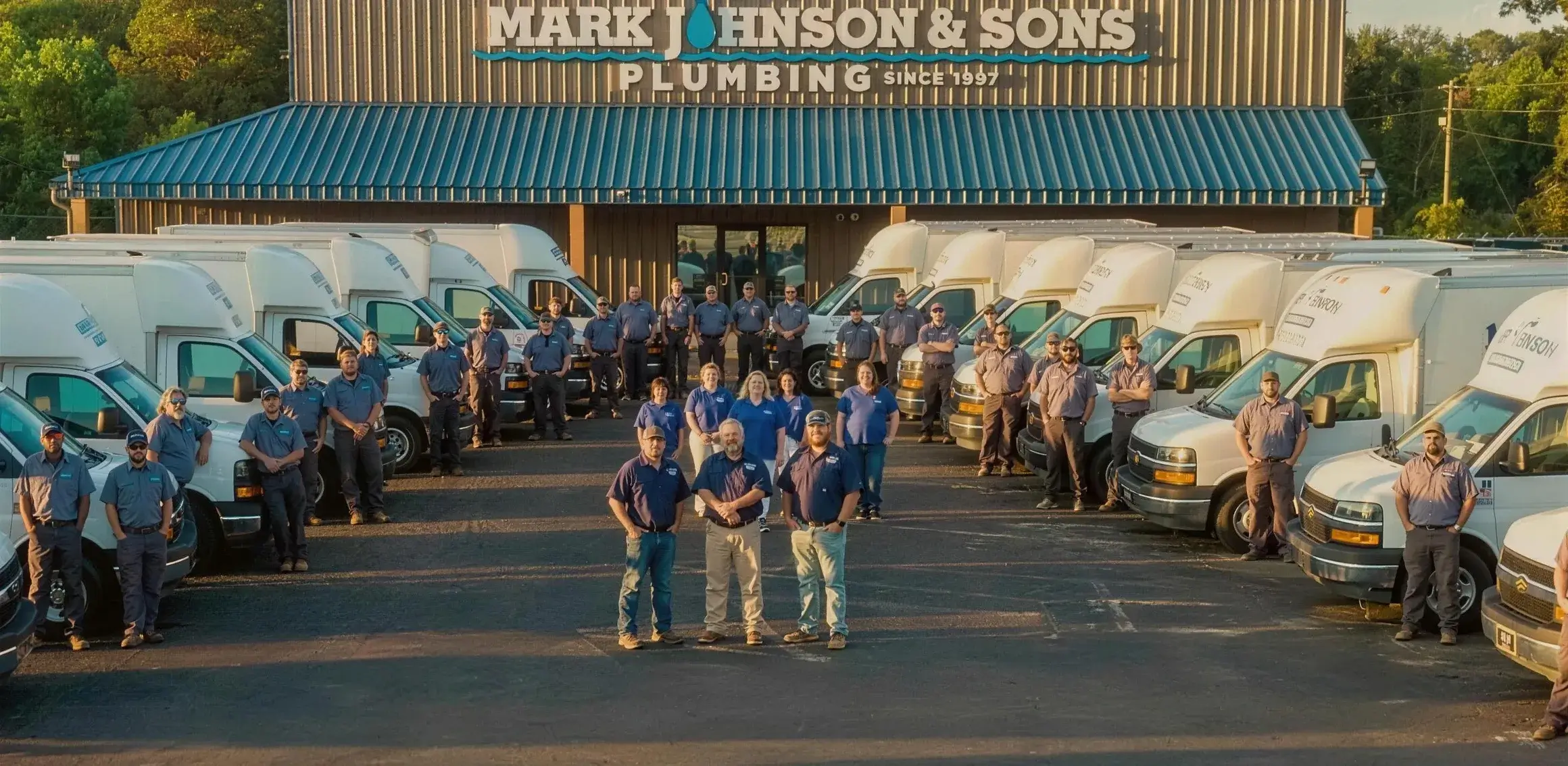 The Mark Johnson & Sons team standing in front of their shop and service trucks